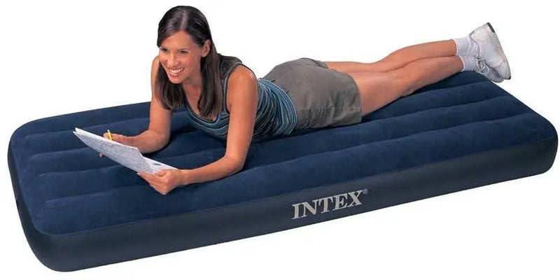 Laad afbeelding in galerijtoner, Een vrouw glimlacht en schrijft op een klembord terwijl ze op een Intex Classic Dura-Beam Eenpersoons Luchtbed van Intex ligt.