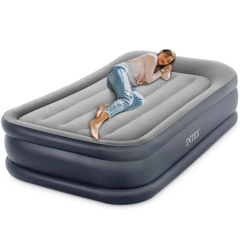 Laad afbeelding in galerijtoner, Een vrouw ontspant op het Intex Pillow Rest Deluxe Eenpersoons Luchtbed, met verhoogde zijkanten en een ingebouwde elektrische pomp voor snel en gemakkelijk opblazen en meer comfort.