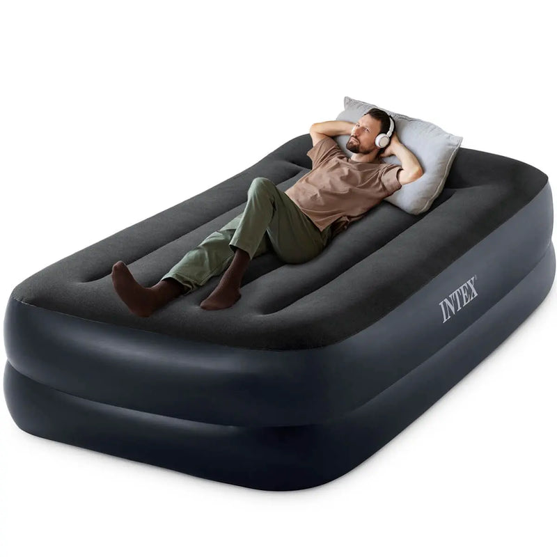 Laad afbeelding in galerijtoner, Man geniet van comfortabel slapen op het Intex Pillow Rest Raised Eenpersoons Luchtbed, terwijl hij ontspannen ligt met een wit kussen en koptelefoon.