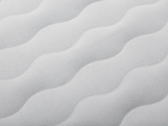 Close-up van een wit gestructureerd oppervlak met zachte, golvende, herhalende ribbels, vergelijkbaar met de Snugable Top op het Bestway Tweepersoons Luchtbed Tough Guard Comfy.