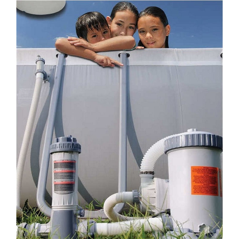 Laad afbeelding in galerijtoner, Drie personen zitten in een grijs opzetzwembad met een grijs met witte automatische chloorverdeler van Interline voor zwembaden gekoppeld aan de filterpomp en aan het zwembad
