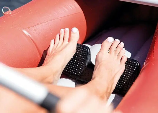 Een close-up van blote voeten op zwarte voetsteunen in een rode Intex Excursion Pro K1 Opblaasbare Kayak