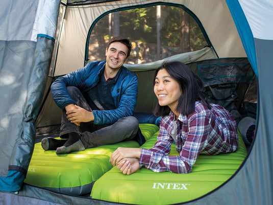 Een man en een vrouw liggen beide op een eigen Een vrouw ligt op een Lichtgroen Intex TruAire Dura-Beam Kampeerluchtbed in een opgezette tent