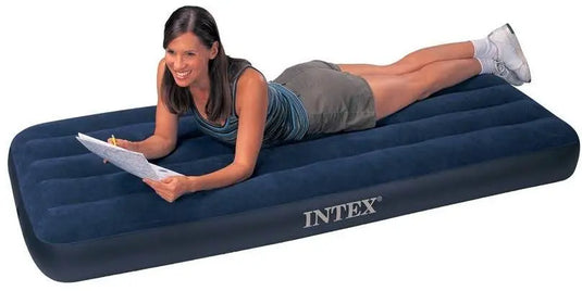 Een vrouw glimlacht en schrijft op een klembord terwijl ze op een Intex Classic Dura-Beam Eenpersoons Luchtbed van Intex ligt.