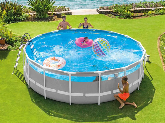 Vier personen genieten van een zonnige dag in het Intex Prism Frame Clearview Zwembad 488 x 122 cm, spelen met drijvers en een strandbal, terwijl het stevige stalen frame van Intex zorgt voor duurzame stabiliteit voor eindeloos zomerplezier.