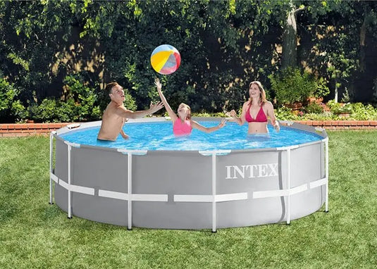 In het Intex Prism Frame Zwembad 366 x 99cm van Intex, inclusief cartridge filterpomp en veilige zwembadladder, spelen drie personen met een strandbal en genieten ze optimaal van hun zonnige achtertuin.