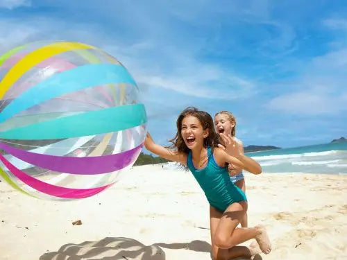 Laad afbeelding in galerijtoner, Twee meisjes spelen met een Intex Strandbal Jumbo op een zonnig strand, met de blauwe zee en de lucht achter zich: de perfecte dag met de Intex strandbal bij het strand en zwembad.
