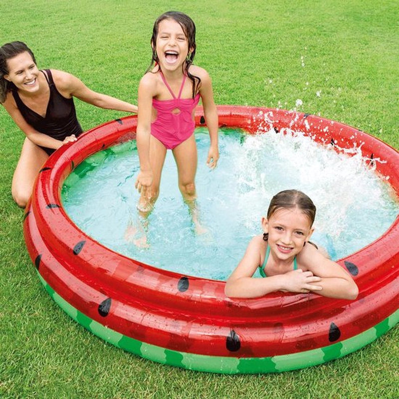 Laad afbeelding in galerijtoner, Twee kinderen zwemmen in een rond opblaasbaar zwembad in de stijl van een watermeloen van Intex waar hun moeder naast het bad zit
