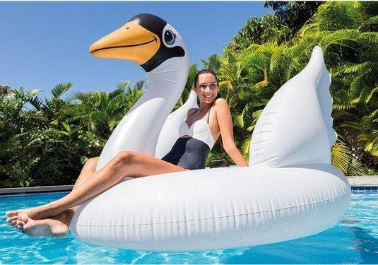 Vrouw zit op een mega opblaasbaar luchtbed in de vorm van een zwaan in een zwembad